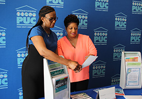 A PUC Consumer Education Specialist speaks with a community event attendee about utilities.